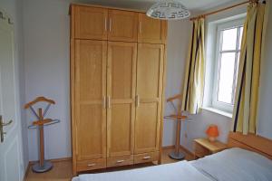 a bedroom with a large wooden cabinet next to a bed at Bernsteinhaus Wohnung Usedom in Kolpinsee