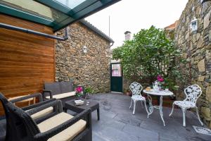 un patio con sedie e tavolo su un muro di pietra di Casa Entera A Ferradura a Melide