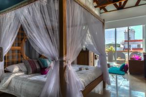 1 dormitorio con cama con dosel y cortinas blancas en Casa de Leda, a Kali Hotel, en Santa Marta