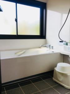 bagno con vasca, lavandino e finestra di Shimanto River House Yuube-Tei a Shimanto