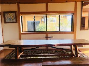 una gran mesa de madera en una habitación con ventana en Shimanto River House Yuube-Tei, en Shimanto
