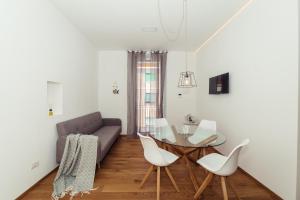 a living room with a glass table and white chairs at Home Diano Marina in Diano Marina