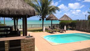 a swimming pool with chairs and umbrellas and the beach at Villa Imperador in João Pessoa