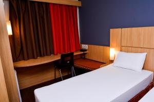 Habitación con 2 camas, escritorio y cortina roja. en Amapá Hotel, en Macapá