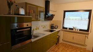 a kitchen with green cabinets and a sink and a window at Ferienwohnung Sandner in Nüdlingen