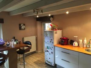 a kitchen with a white refrigerator and a table at La grange in La Houssière