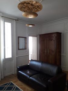 - un canapé en cuir noir dans un salon avec deux fenêtres dans l'établissement Résidence Helianthe, à Biarritz