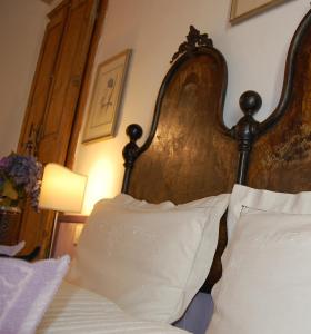 a bed with white pillows and a wooden head board at Agriturismo L'Aglientu B&B in Loiri