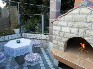 a patio with a stone fireplace and a table and a bench at Apartman Radic in Ston