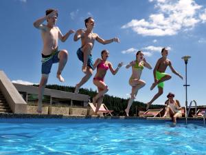 a group of people jumping into a swimming pool at Horský Hotel Kopřivná in Malá Morávka