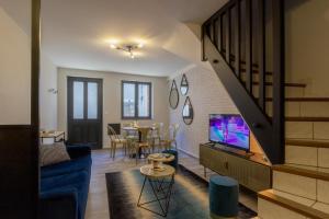 ein Wohnzimmer mit einem blauen Sofa und einem TV in der Unterkunft Maison de centre ville in Souillac