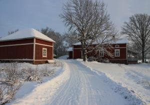 una carretera cubierta de nieve junto a un granero rojo en Leipyölin tila en Perniö