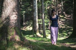 Una mujer caminando por un camino en el bosque en Da Elda Natural Retreat, en Ledro