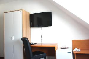 a living room with a television and a desk at Hotel Batavia in Düsseldorf