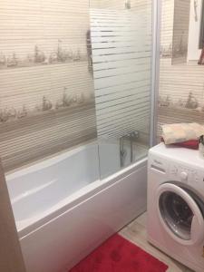 a bathroom with a tub and a washing machine at Apartament Rosenau in Râşnov +8 photos