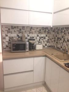 a kitchen with white cabinets and a microwave on a counter at Apartament Rosenau in Râşnov