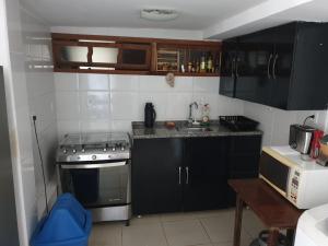 a small kitchen with black cabinets and a stove at Lindo Apartamento em Buzios in Búzios
