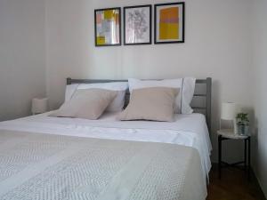 ein Bett mit weißen Laken und Kissen in einem Schlafzimmer in der Unterkunft Apartman Oleander in Split