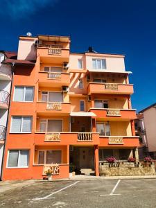 un edificio de apartamentos naranja con aparcamiento en Guest House Rai en Kiten