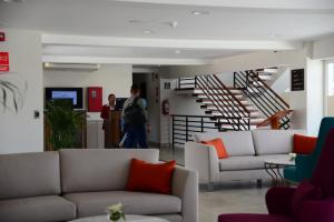 a man walking through a living room with couches and stairs at DM Hoteles Moquegua in Moquegua