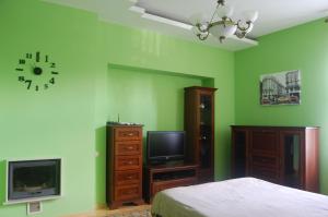 Schlafzimmer mit grünen Wänden, einem Bett und einem TV in der Unterkunft Na Katedralniy in Lwiw