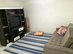 a living room with a couch and a television at Aconchego e conforto em Joanópolis in Joanópolis