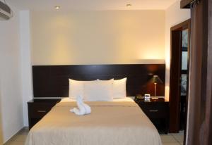 una camera d'albergo con un letto con un cigno bianco sopra di Hotel Villa Florencia Zona Rosa a San Salvador