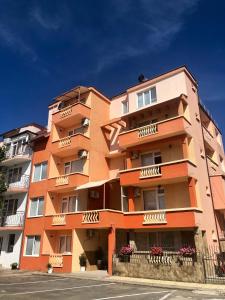 un gran edificio naranja con balcones en una calle en Guest House Rai en Kiten