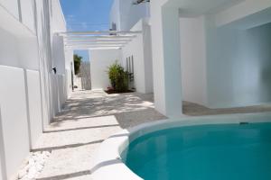 a white house with a swimming pool in a yard at Kapetan Tasos Suites in Pollonia