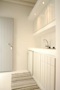 una cocina con armarios blancos, fregadero y alfombra en Kapetan Tasos Suites en Pollonia