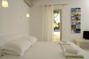 a white bedroom with a bed and a window at Kapetan Tasos Suites in Pollonia