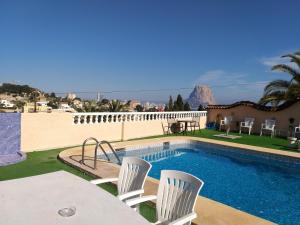 a swimming pool with white chairs and a table at Apartamentos El Tosal 7E in Calpe