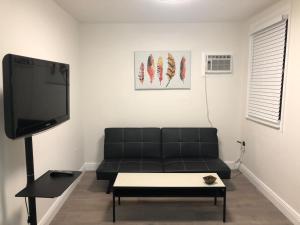 a living room with a black couch and a flat screen tv at Close to Everything Miami in Miami
