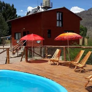 two chairs and two umbrellas on a deck next to a house at Solanas de Uspallata in Uspallata