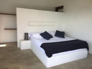 a white bedroom with a white bed with blue pillows at Villas La Antigua Barichara in Barichara +31 photos