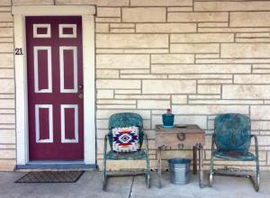 two chairs and a table next to a red door at Hotel Kitsmiller on Main in Fredericksburg