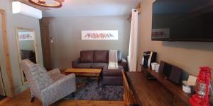 a living room with a couch and a television at Auberge le Cosy in La Conception