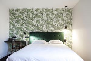 a bedroom with a white bed with a green headboard at Logis Hotel du Maine in Laval