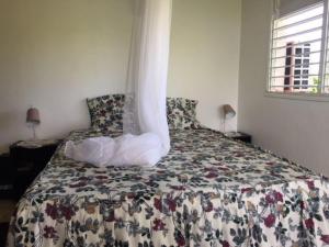 a bedroom with a bed with a flowered blanket and a window at Sunshine Villa in Le Moule