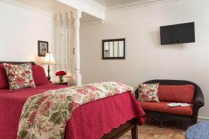 a bedroom with a red bed and a chair at Cheshire Cat Inn & Cottages in Santa Barbara