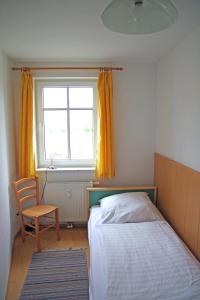1 dormitorio con 1 cama, 1 silla y 1 ventana en Bernsteinhaus Wohnung Usedom en Kolpinsee