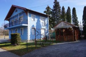 a blue house with a gate and a building at Atlas Apartman in Bük