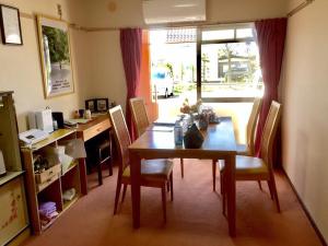 a dining room with a table and chairs and a desk at Backpackers Dorms Miwa Apartment in Nagano