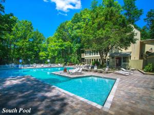 a large swimming pool with lounge chairs and trees at Rocky Top Lodge, 6 Bedrooms, Pool Access, Hot Tub, Mountain View, Sleeps 14 in Gatlinburg