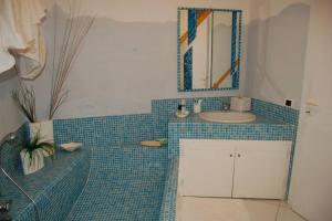 bagno piastrellato blu con lavandino e specchio di Apt. Marilena by SolturElba a Capoliveri Altre 12 foto