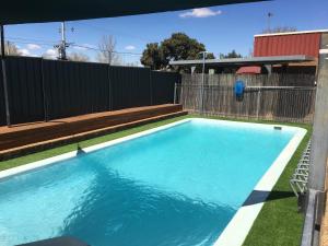 a swimming pool in a backyard with a fence at Camellia Motel in Narrandera