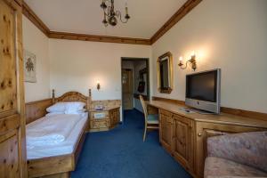 um quarto com uma cama e uma televisão de ecrã plano em Hotel Alpina - Thermenhotels Gastein em Bad Hofgastein