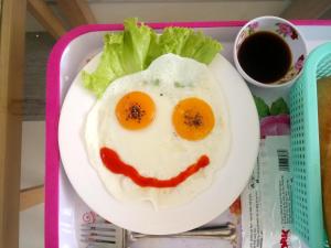 a plate of food with an egg and a smiley face at Hung Long Hotel in Ben Tre