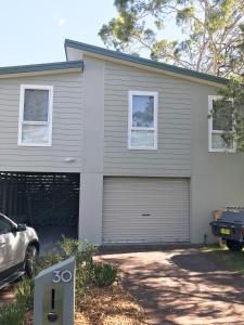 een huis met een garage met een bord ervoor bij The Lake Guesthouse in Budgewoi