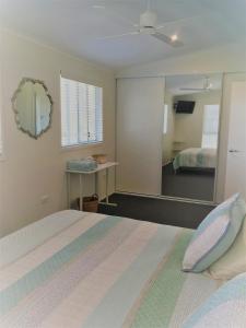 um quarto com uma cama e um espelho em The Lake Guesthouse em Budgewoi